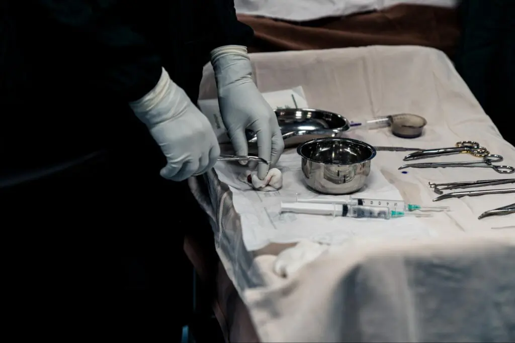 A person in medical gloves prepares surgical tools on a tray covered with a sterile cloth; syringes, forceps, and metal bowls are visible on the table, ready for reconstructive surgery that saved a man’s leg in Ethiopia.