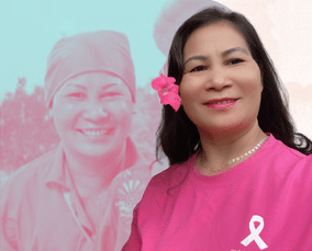 A woman wearing a pink shirt with a breast cancer ribbon smiles at the camera, highlighting the journey of breast cancer care, with a pink-toned image of herself in a headscarf in the background and a pink flower in her hair.