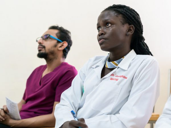 Two individuals attentively listening to a lecture while seated on chairs