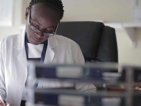 A female doctor in white coat writing on a paper